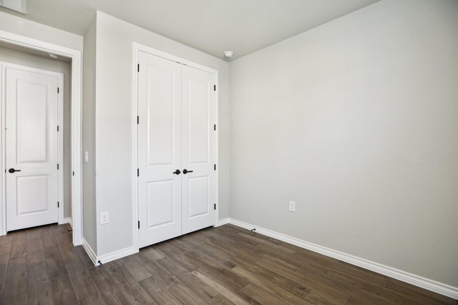 Unfurnished bedroom with dark wood-style floors and a closet Unfurnished bedroom with dark wood-style floors and a closet