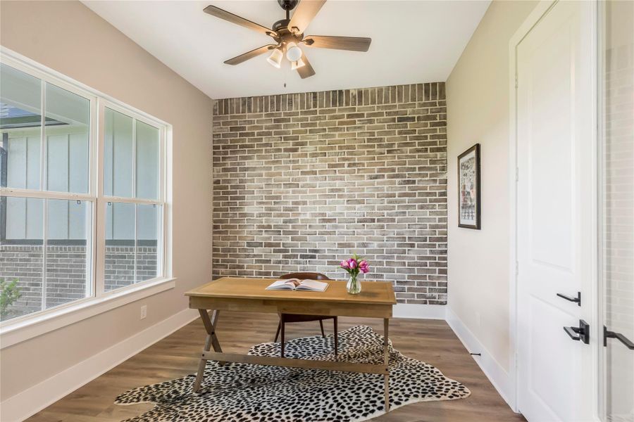 Charming study featuring a stylish brick accent wall.