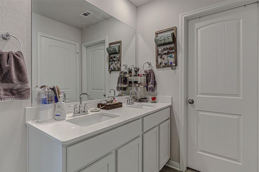 Full bath featuring a textured wall and double vanity