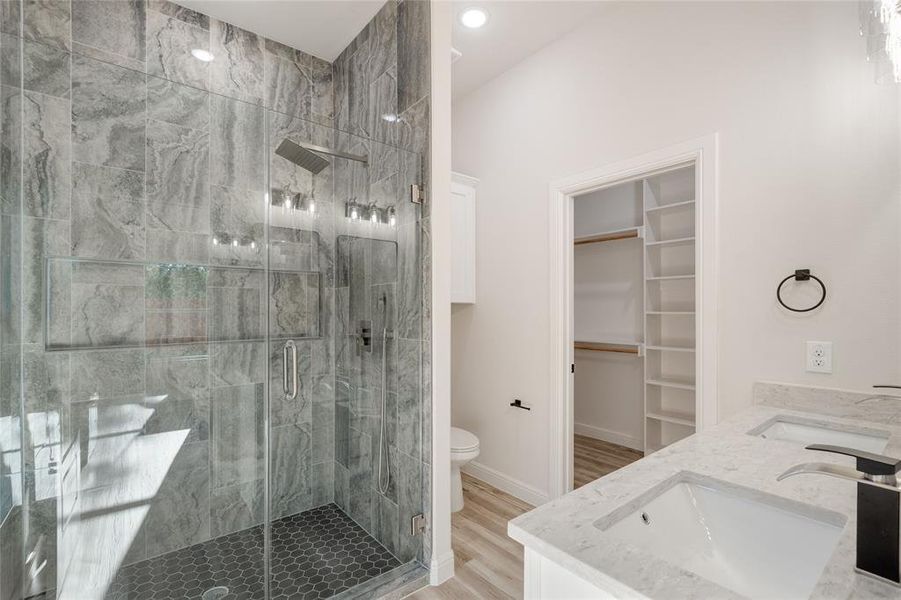 Main bathroom with a spacious closet, double vanity, a stall shower, and light wood finished floors