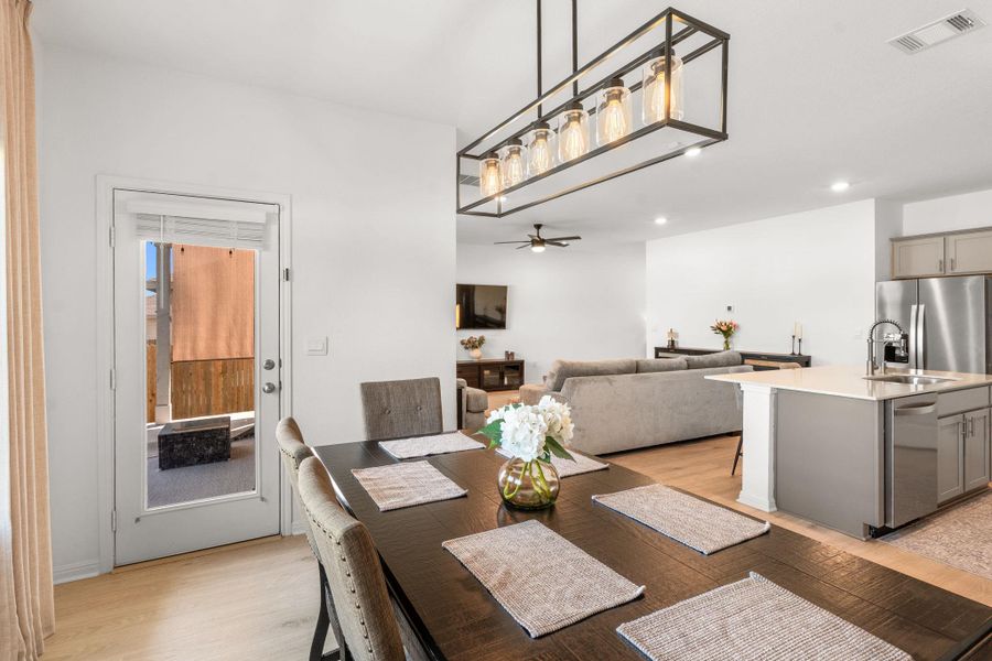 Natural light illuminates an open-concept living area, seamlessly connecting a dining space to a modern kitchen. Natural light illuminates an open-concept living area, seamlessly connecting a dining space to a modern kitchen.