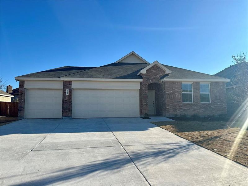 Ranch-style home with a garage, concrete driveway, brick siding, and roof with shingles