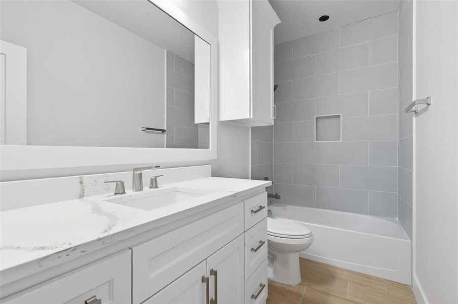 Bathroom with vanity, washtub / shower combination, and wood finish floors Bathroom with vanity, washtub / shower combination, and wood finish floors