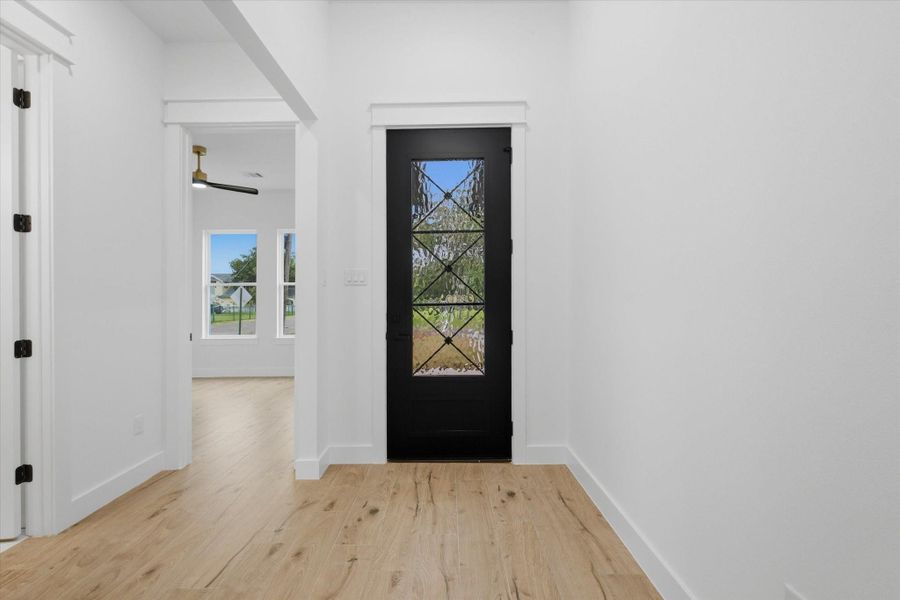 Welcome Home! Make a striking first impression with this bright and airy foyer, featuring a gorgeous black steel-and-glass entry door that lets in beautiful natural light while maintaining privacy. Seamless light oak-style flooring guides you effortlessly into the rest of the home.