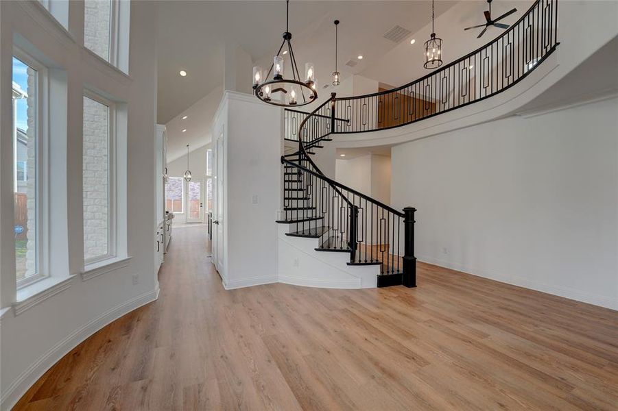 Entrance foyer featuring baseboards, vinyl flooring, a towering ceiling, and an inviting chandelier