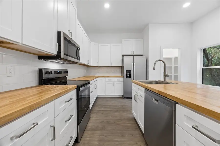 A well-equipped culinary space boasts ample white cabinetry and warm wooden countertops.