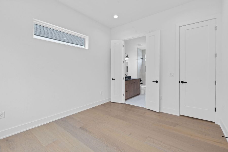 Unfurnished bedroom with light wood finished floors, ensuite bath, and recessed lighting