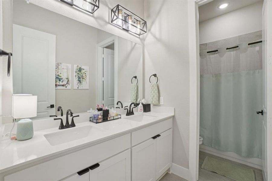 Secondary bathroom featuring double vanity with separate toilet and shower/tub combo area.