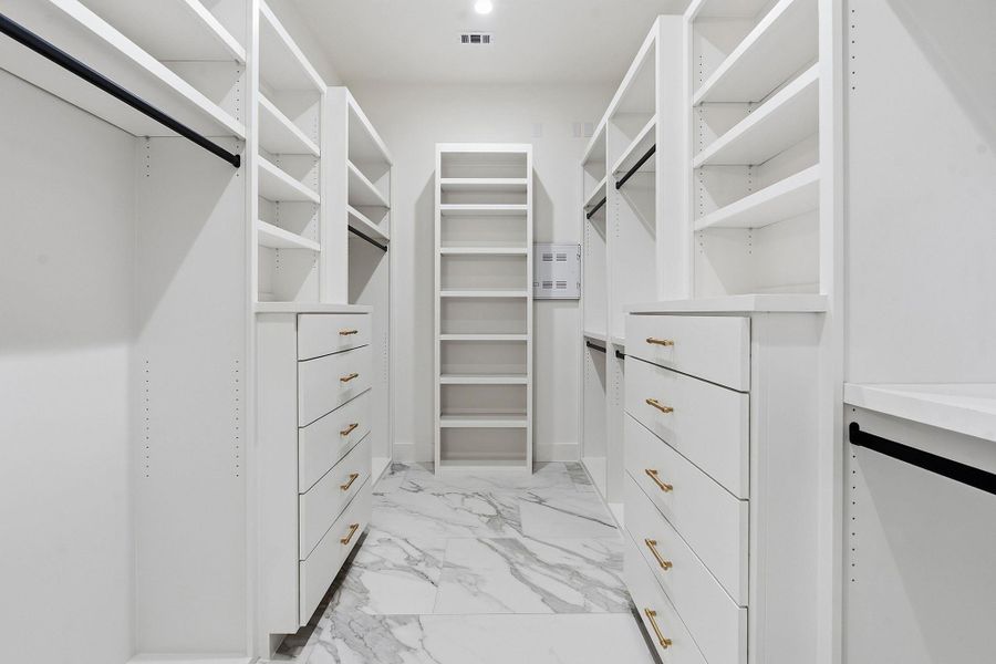 Marble-patterned tile flooring elevates this custom closet featuring extensive built-in shelving and drawer storage.