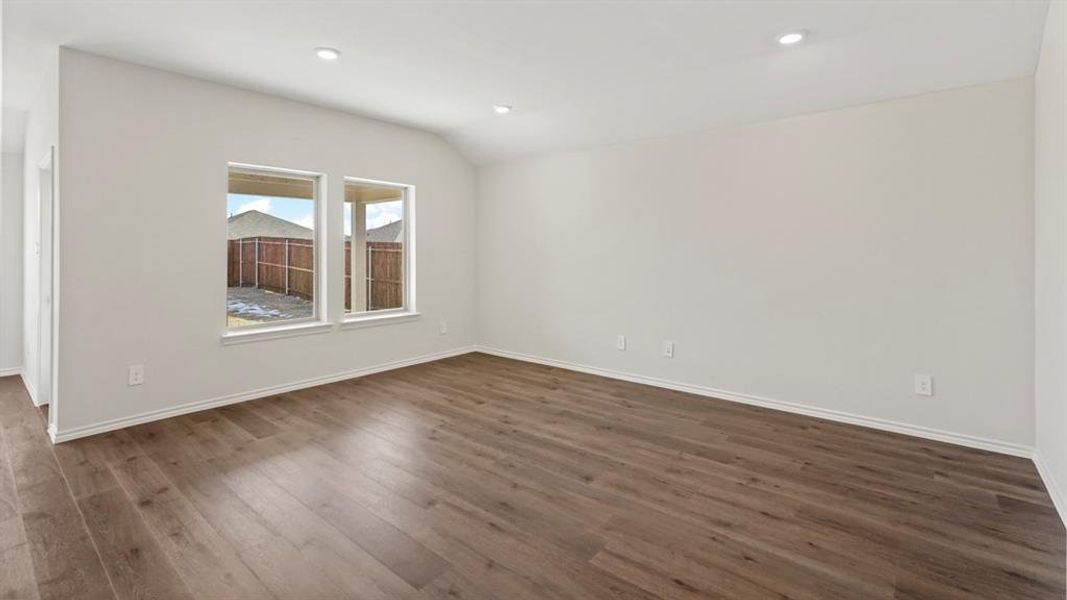 Spacious interior room featuring wood-finish flooring, white walls, and a recessed lighting system