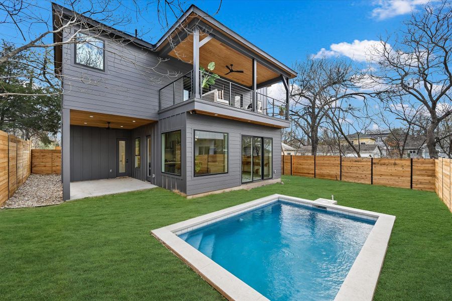 The rear elevation showcases the homes striking architectural profile. Large glass sliders and expansive windows create a transparent connection between the high-end interior and the luxury backyard retreat.