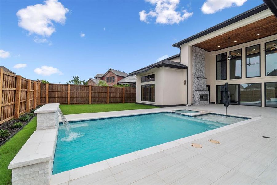 View of swimming pool with pool water feature, a patio area, ceiling fan, and a lawn