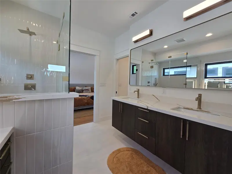 Ensuite bathroom with visible vents, a sink, double vanity, and a tile shower Ensuite bathroom with visible vents, a sink, double vanity, and a tile shower