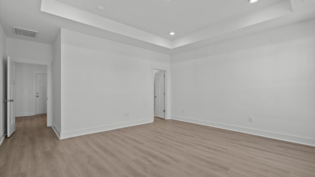 Eye-catching details, tray ceiling, and elegant finishes in the vibrant primary suite of this select home