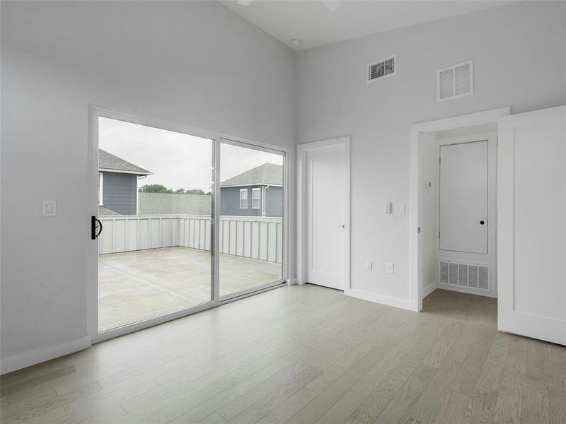 The luxurious primary bedroom features a vaulted ceiling and elegant wood flooring, offering a serene retreat for relaxation and rejuvenation.