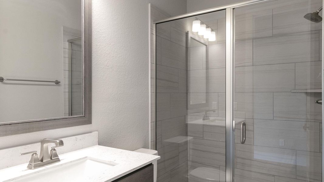 Bathroom featuring a textured wall, vanity, and a stall shower