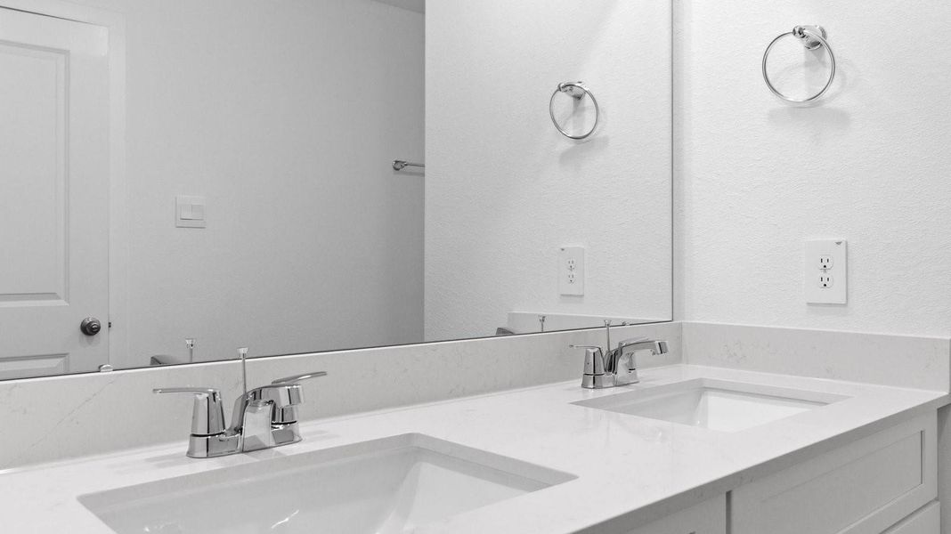 primary bathroom with double vanities, granite countertops, and a glass-enclosed shower with a walk-in closet.
