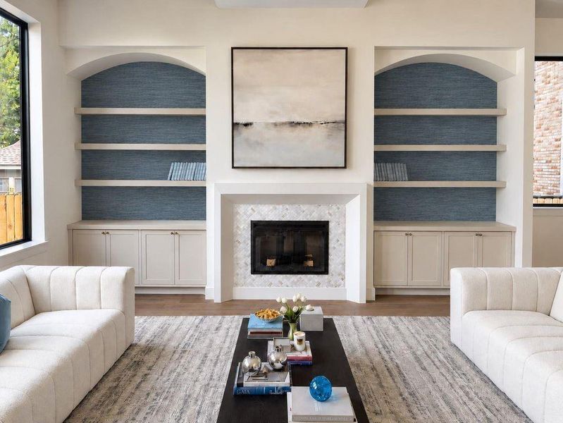 Custom build ins in the living room lined with grasscloth wallpaper, custom plastered mantle and marble surround