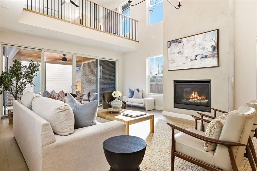 Living area featuring a glass covered fireplace, a high ceiling, and wood finished floors
