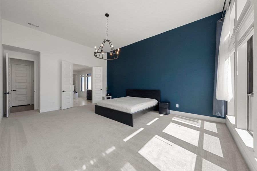 Unfurnished bedroom featuring a chandelier, light colored carpet, visible vents, and multiple windows