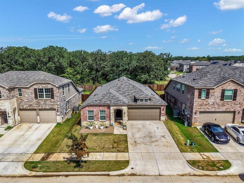 View of front of property featuring a garage, driveway, brick siding, and a residential view
