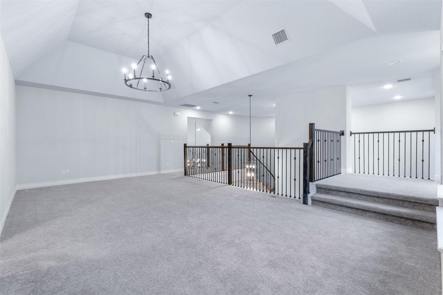 Carpeted empty room with a chandelier and baseboards