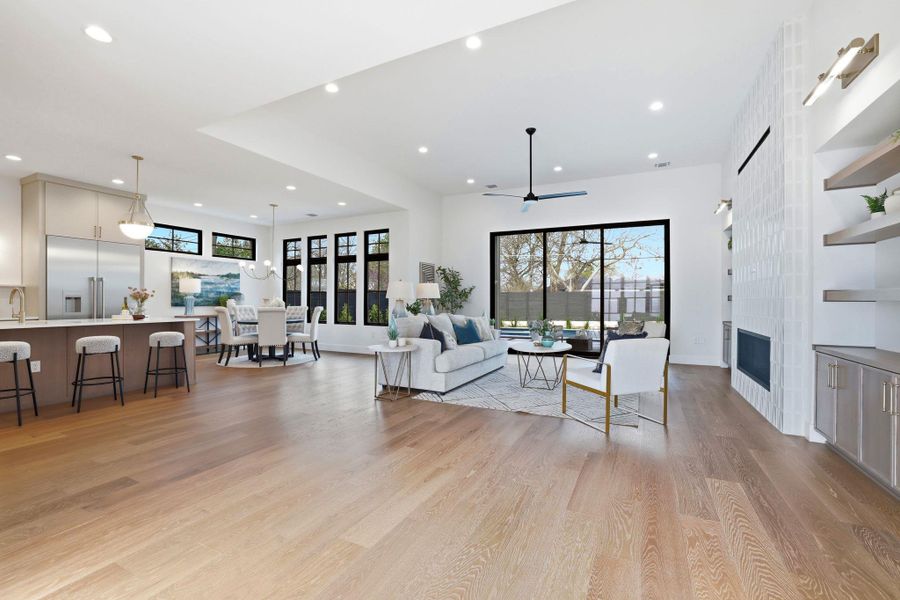 Living area with a fireplace, light wood-type flooring, a ceiling fan, and recessed lighting