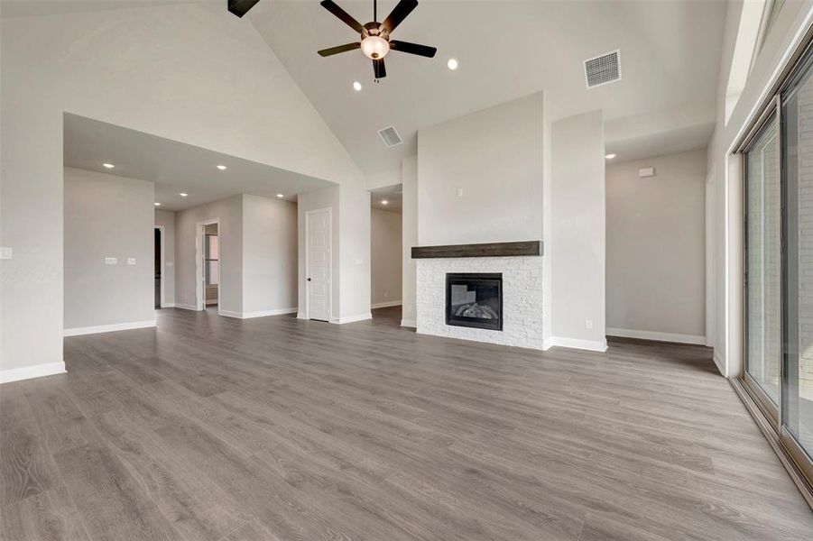 Spacious living area featuring wood-finish flooring, a vaulted ceiling, and a ceiling fan