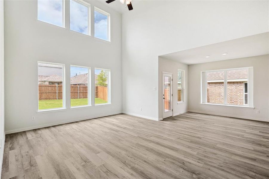 Unfurnished living room with a towering ceiling, light wood-type flooring, and ceiling fan