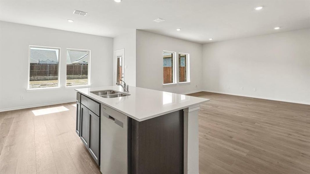 The kitchen features a center island with a double basin sink and a dishwasher, complemented by light-colored flooring