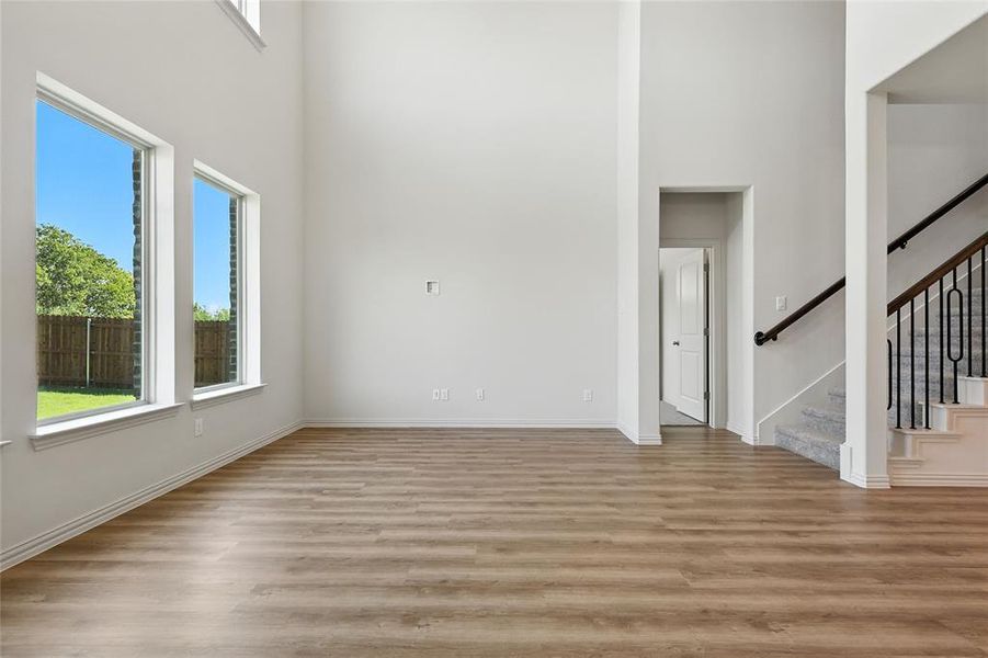 Unfurnished living room with stairway, a high ceiling, and light wood finished floors