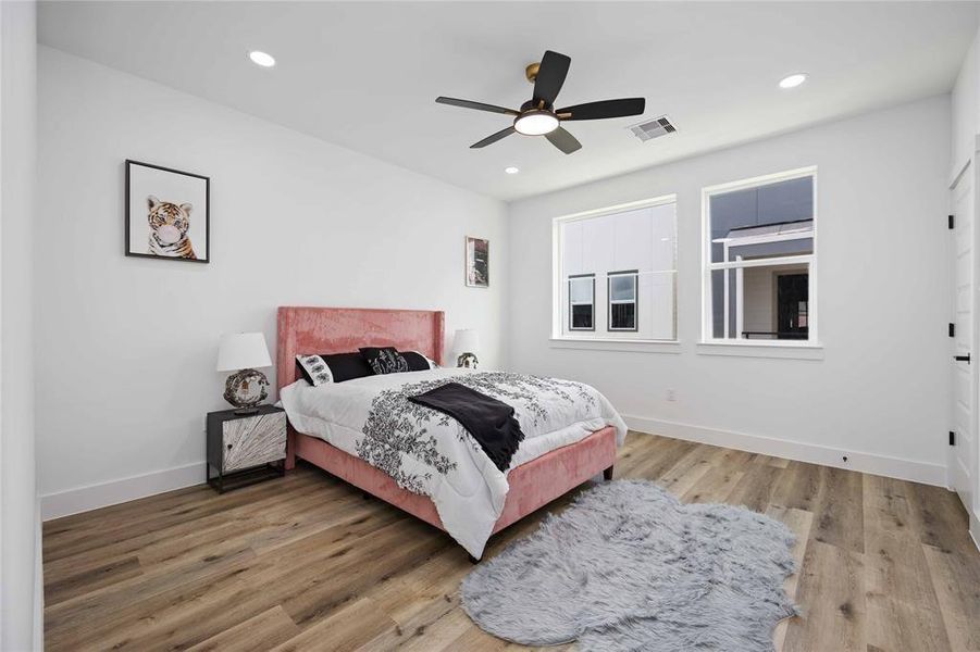 The oversized third bedroom showcases upgraded floors, a ceiling fan, and large picture windows.