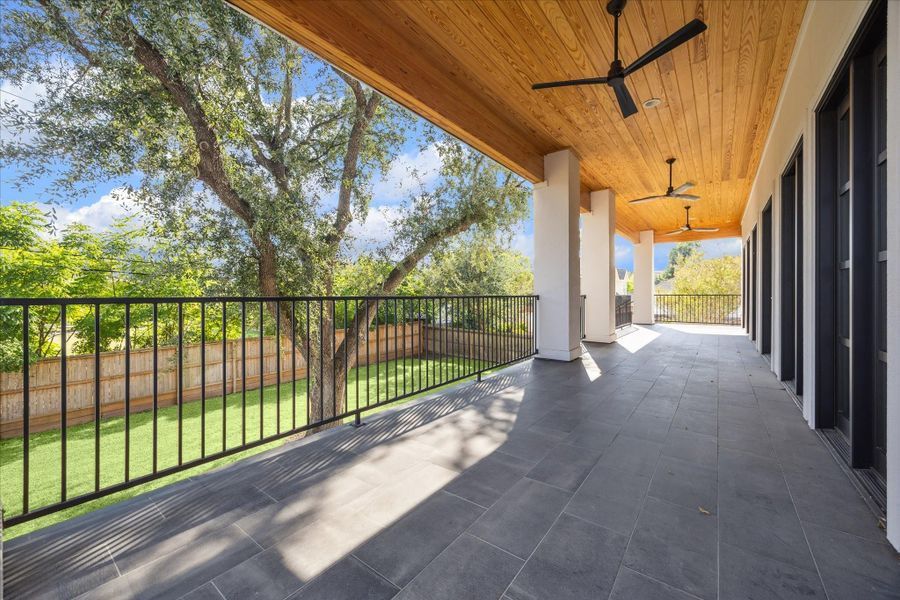 First floor porch alongside the family room and kitchen spans the width of the home with a staircase leading to ground level. With the wood paneled ceiling, several ceiling fans and tile flooring, this space is perfect to have a morning coffee or evening cocktail and watching kids and pets play! First floor porch alongside the family room and kitchen spans the width of the home with a staircase leading to ground level. With the wood paneled ceiling, several ceiling fans and tile flooring, this space is perfect to have a morning coffee or evening cocktail and watching kids and pets play!