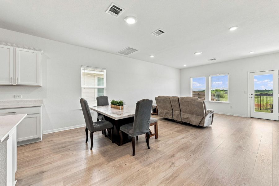 An open floorplan design seamlessly connects the dining and living spaces over wood flooring.