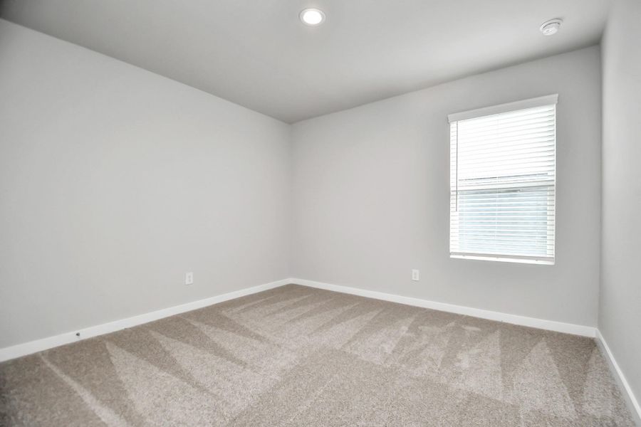 Secondary bedroom features plush carpeting, large windows that let in plenty of natural light, bright paint, and spacious closets. Sample photo of completed home with similar floor plan. Actual colors and selections may vary.