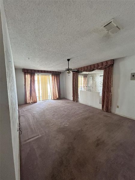 Unfurnished room with a textured ceiling, carpet flooring, and ceiling fan Unfurnished room with a textured ceiling, carpet flooring, and ceiling fan