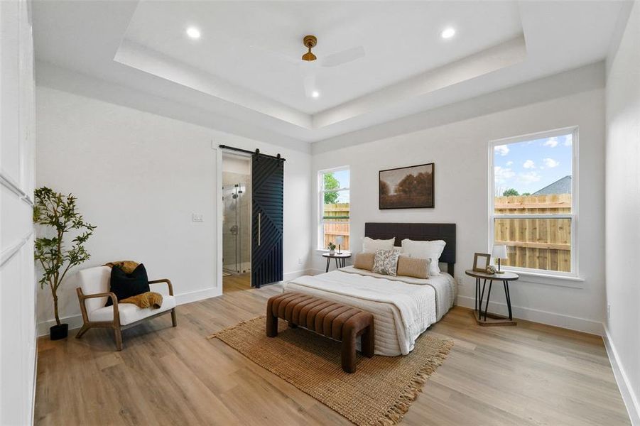 Spacious room featuring wood-finish flooring, a tray ceiling with recessed lighting, and a modern ceiling fan