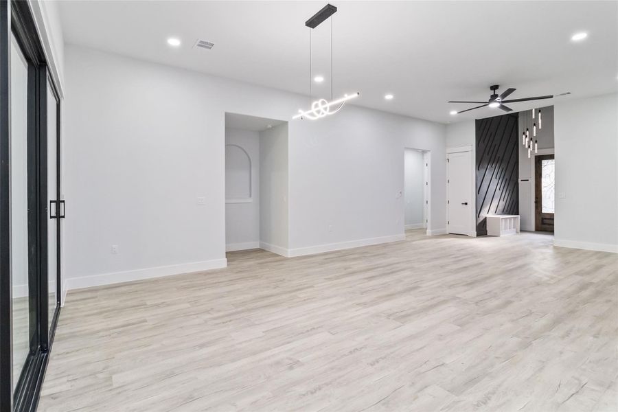 Spare room featuring light wood-type flooring, recessed lighting, ceiling fan, and a chandelier