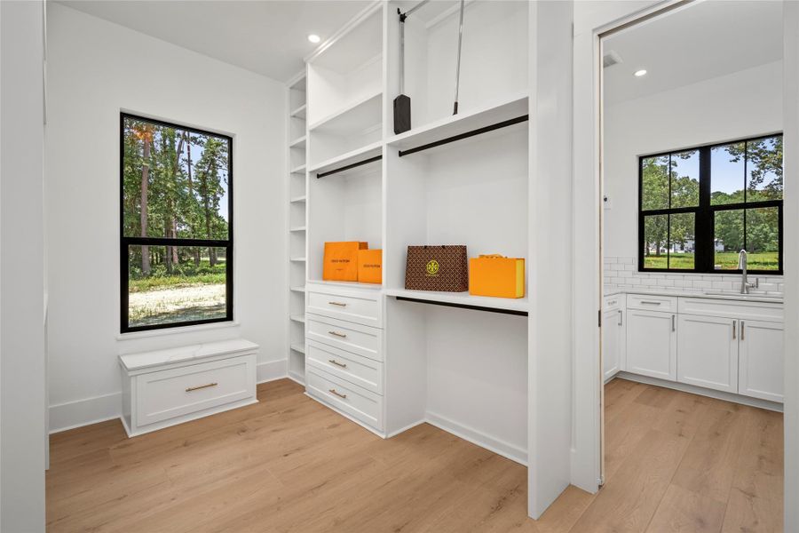 Luxurious primary suite with separate walk-in closets, built-in drawers, and a window seat overlooking wooded views. Luxurious primary suite with separate walk-in closets, built-in drawers, and a window seat overlooking wooded views.