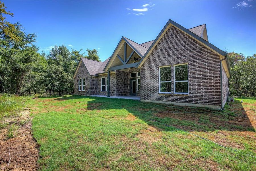 View of front of home featuring brick siding, a patio, a front lawn, and ceiling fan View of front of home featuring brick siding, a patio, a front lawn, and ceiling fan