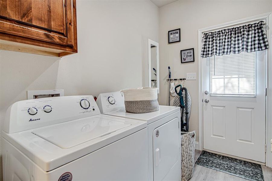 Washroom with cabinets, light wood-type flooring, and washing machine and clothes dryer