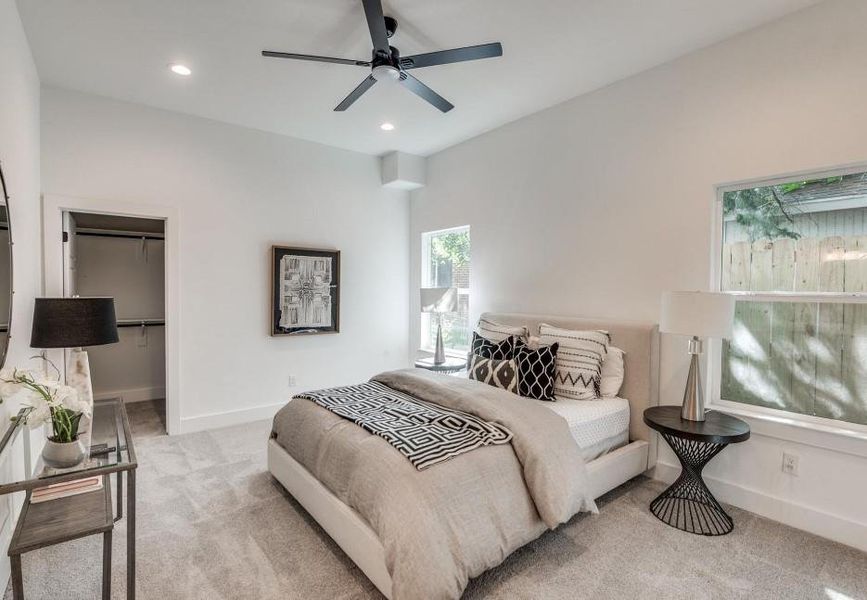 Carpeted bedroom featuring a closet, a spacious closet, and ceiling fan