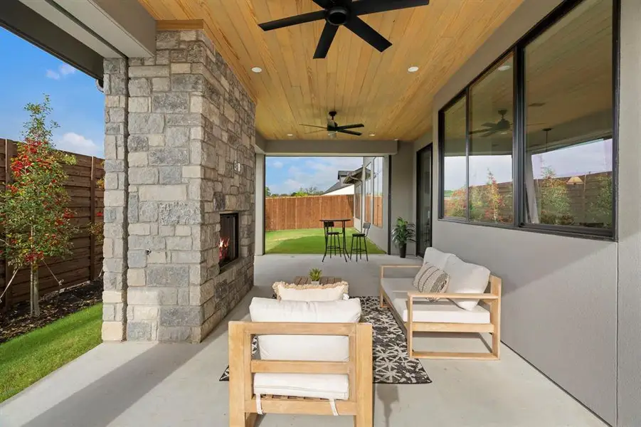 Fenced backyard featuring a patio area, an outdoor living space with a fireplace, and a ceiling fan Fenced backyard featuring a patio area, an outdoor living space with a fireplace, and a ceiling fan