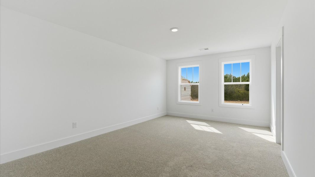 Bright and serene bedroom with comfortable carpeted flooring and large windows for vibrant light at this home at Foxbank
