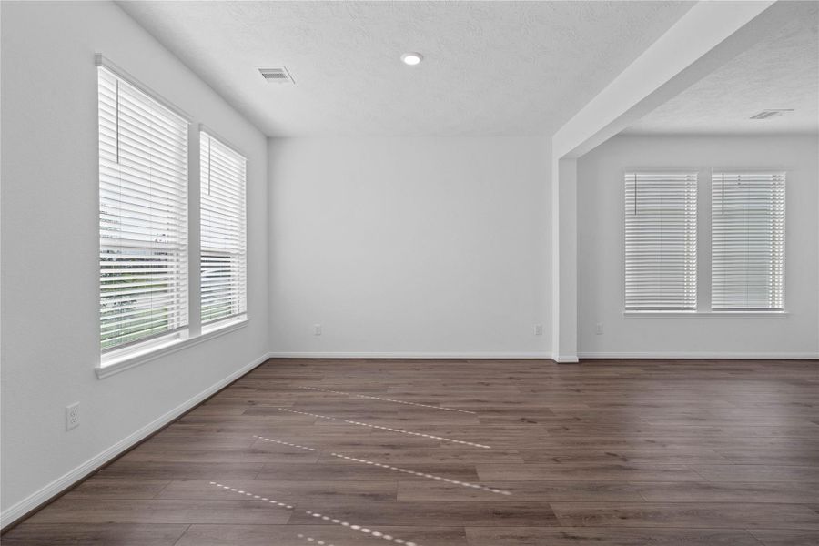 Gather and unwind in this spacious living room, designed with both comfort and style in mind. Large windows flood the space with natural light, creating a warm atmosphere that complements the beautiful flooring and neutral color palette.