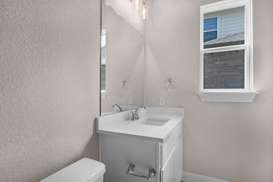 Half bath with a textured wall, toilet, and vanity Half bath with a textured wall, toilet, and vanity