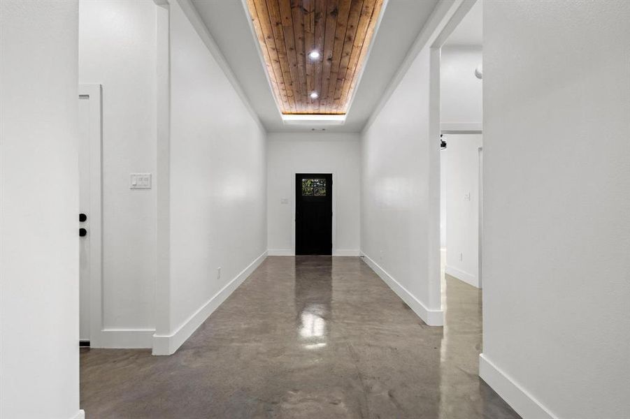 Entryway featuring finished concrete flooring, a raised ceiling, and recessed lighting