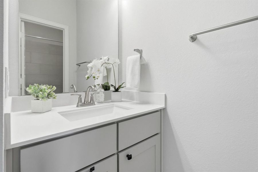 A stylish quartz vanity with shaker-style cabinetry, designer fixtures, and generous counter space complements the upstairs bathroom, offering both beauty and everyday functionality.