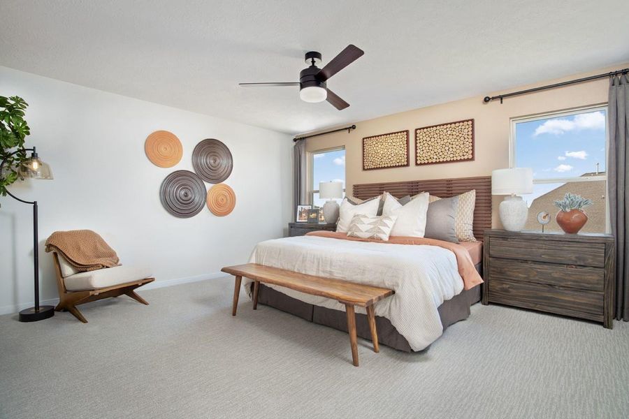 What a wonderful place to come home to, this stunning primary suite greets you with carpet flooring, a neutral custom paint, high ceiling with ceiling fan, large windows allowing in natural light brightening up this spacious bedroom, with extra space for a seating area.