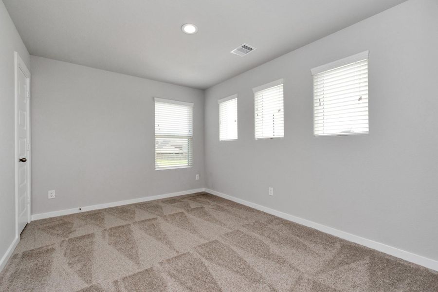 Secondary bedrooms showcase 5-panel doors adorned with modern hardware, large windows enhanced by privacy blinds, and spacious closets featuring sleek and contemporary finishes. Sample photo of completed home with similar floor plan. Actual colors and selections may vary.